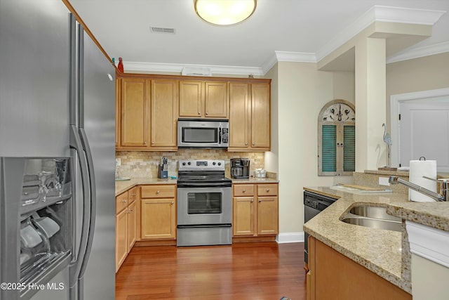 kitchen featuring light stone countertops, ornamental molding, stainless steel appliances, sink, and hardwood / wood-style flooring