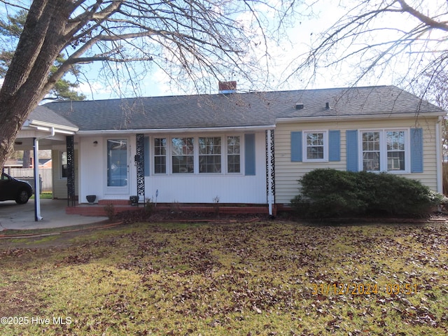 single story home with roof with shingles, a carport, and a chimney