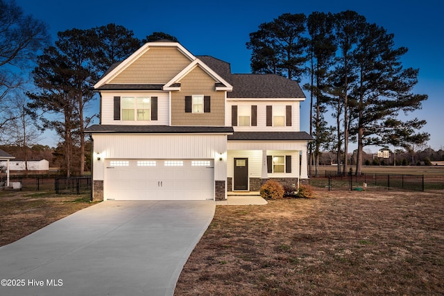 craftsman-style house featuring stone siding, driveway, fence, and an attached garage