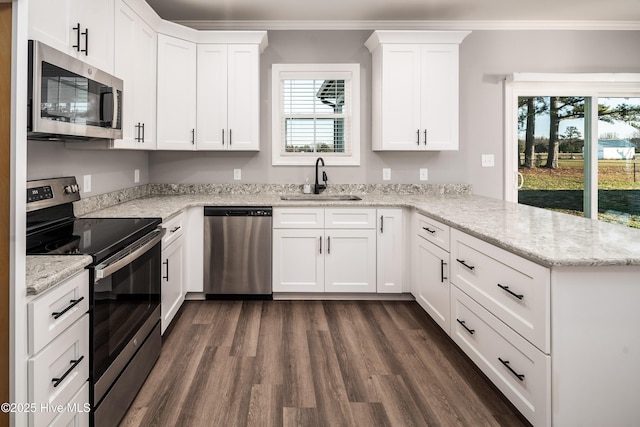 kitchen with white cabinetry, stainless steel appliances, kitchen peninsula, and sink