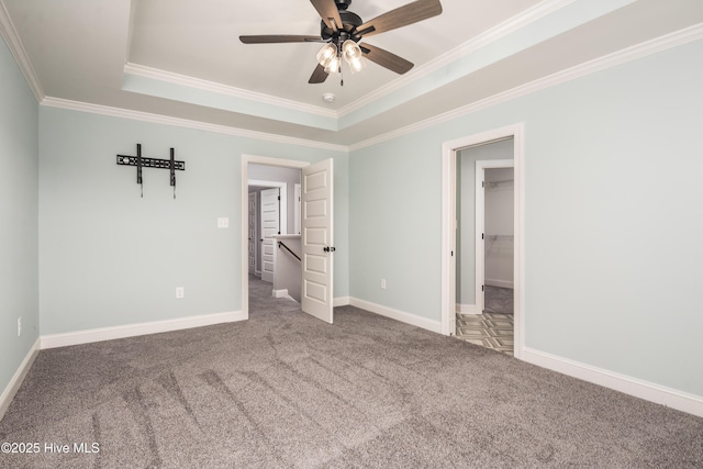 unfurnished bedroom featuring carpet floors, ornamental molding, a raised ceiling, and ceiling fan