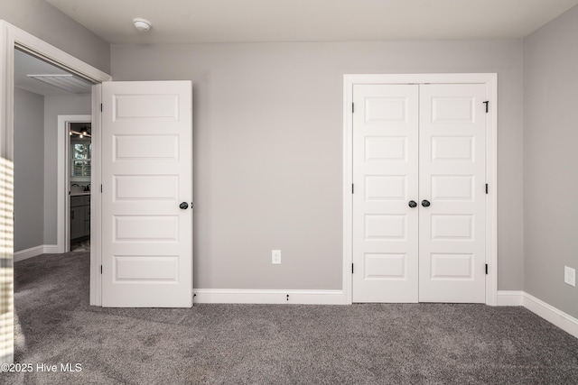 unfurnished bedroom featuring dark carpet and a closet