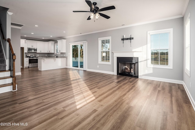 unfurnished living room with hardwood / wood-style floors, crown molding, and a wealth of natural light