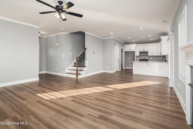 unfurnished living room featuring sink, crown molding, and dark hardwood / wood-style floors