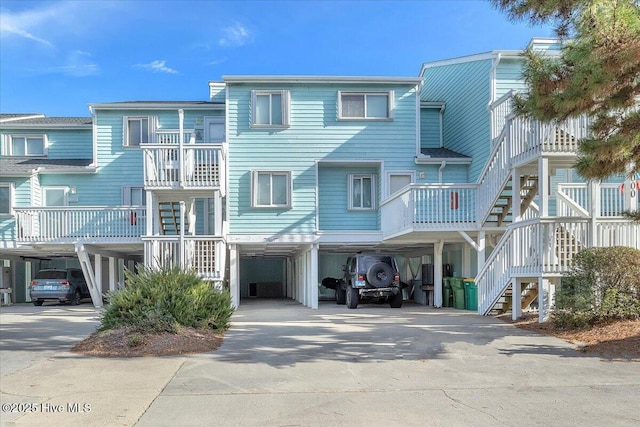 view of front of home featuring a carport, concrete driveway, and stairs