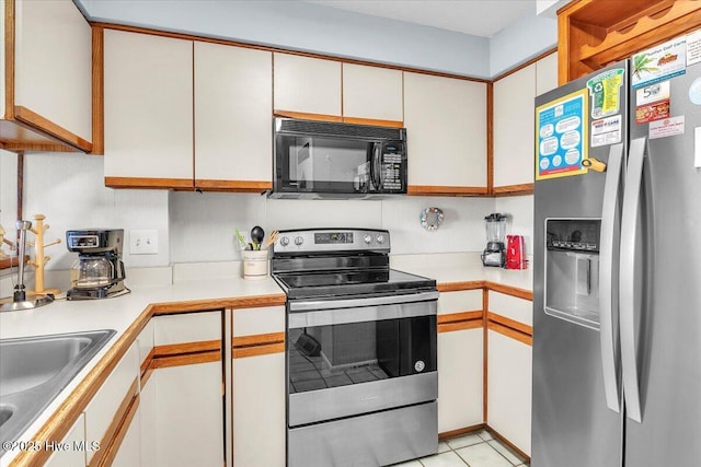 kitchen featuring sink, white cabinets, stainless steel appliances, and light tile patterned floors