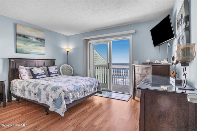 bedroom featuring light hardwood / wood-style floors, access to exterior, and a textured ceiling