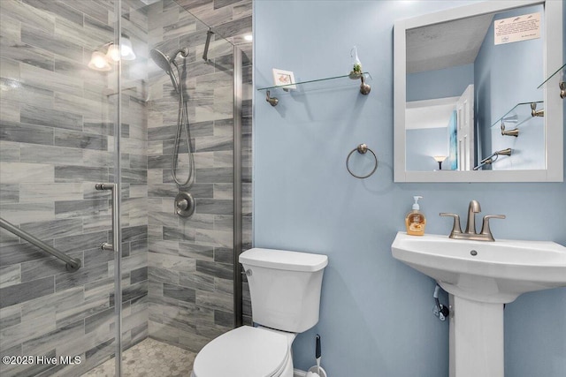 bathroom featuring a shower with door and toilet