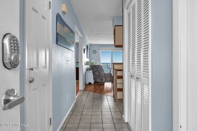 corridor with tile patterned flooring and a textured ceiling