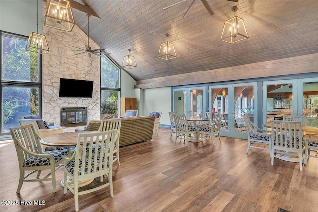 dining space with ceiling fan, wood ceiling, a fireplace, and high vaulted ceiling