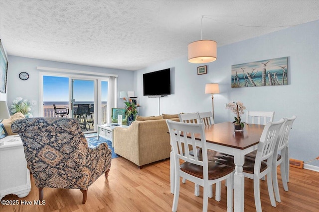 dining area featuring a textured ceiling and light hardwood / wood-style flooring