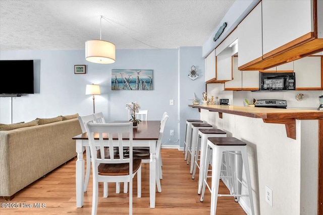 dining area featuring light wood-type flooring and a textured ceiling