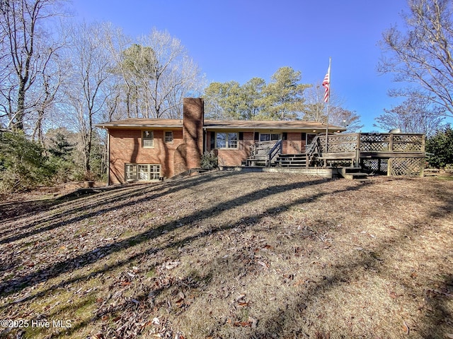 rear view of house featuring a lawn and a deck