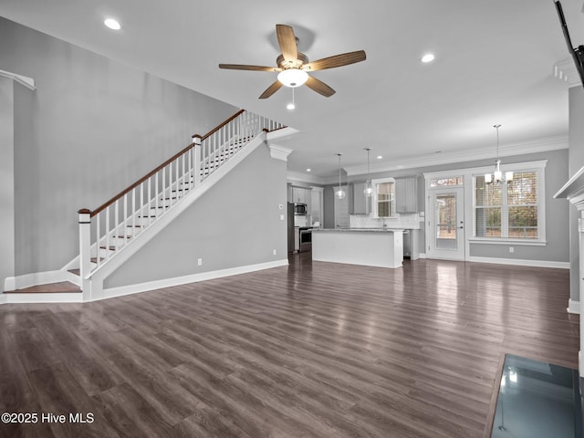 unfurnished living room with crown molding, dark hardwood / wood-style flooring, and ceiling fan with notable chandelier