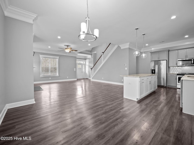 kitchen with gray cabinetry, stainless steel appliances, decorative light fixtures, a kitchen island, and ceiling fan with notable chandelier