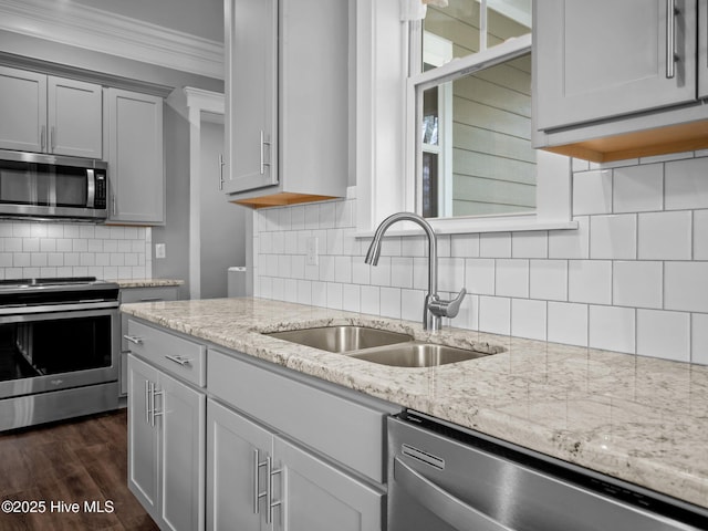 kitchen with light stone counters, ornamental molding, sink, and appliances with stainless steel finishes