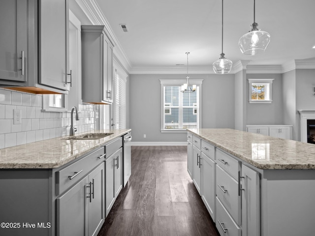 kitchen featuring pendant lighting, sink, stainless steel dishwasher, gray cabinets, and a kitchen island