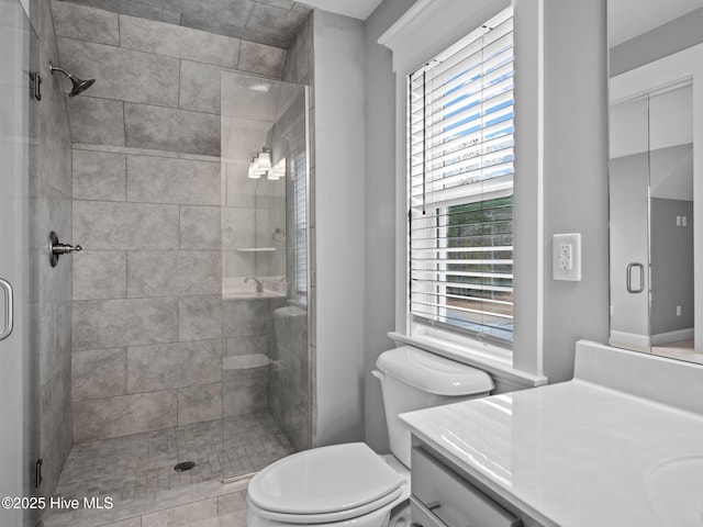 bathroom featuring a shower with door, vanity, a healthy amount of sunlight, and toilet