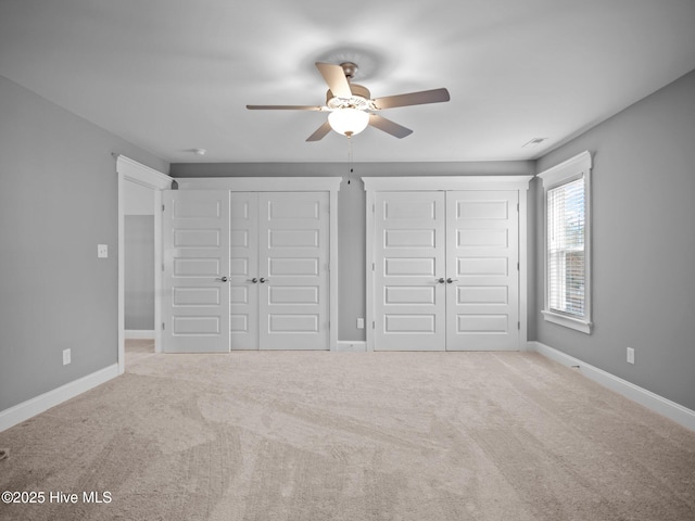 unfurnished bedroom with multiple closets, ceiling fan, and light carpet