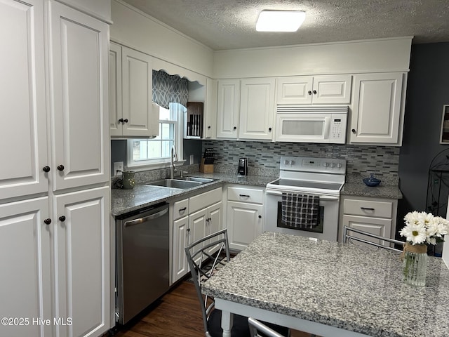 kitchen with dishwasher, backsplash, sink, range with electric cooktop, and white cabinetry