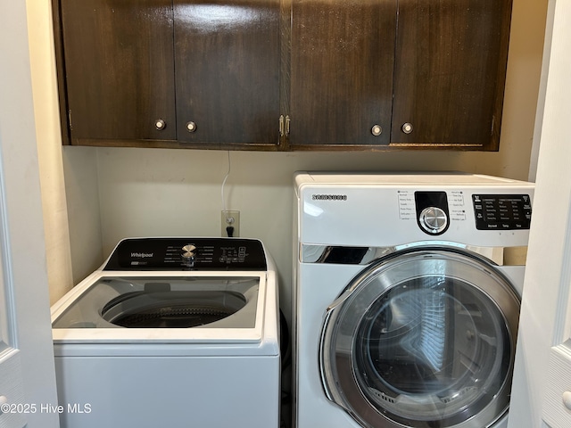 clothes washing area with washer and dryer and cabinets