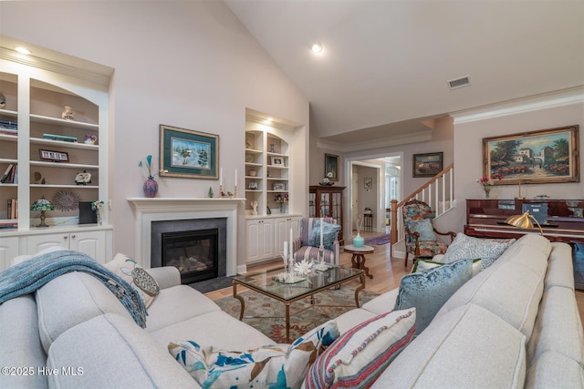 living room with built in features, light hardwood / wood-style floors, and vaulted ceiling