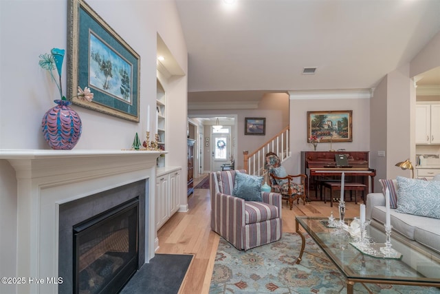 living room with light wood-type flooring and ornamental molding