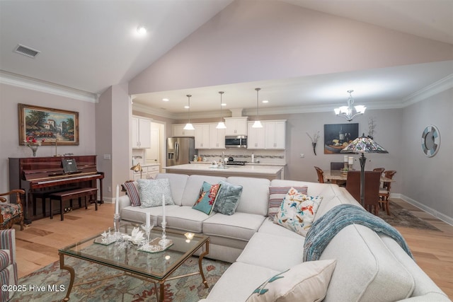 living room with ornamental molding, light wood-type flooring, an inviting chandelier, and vaulted ceiling