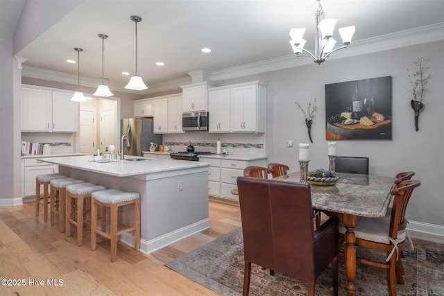 kitchen with backsplash, white cabinetry, stainless steel appliances, and hanging light fixtures