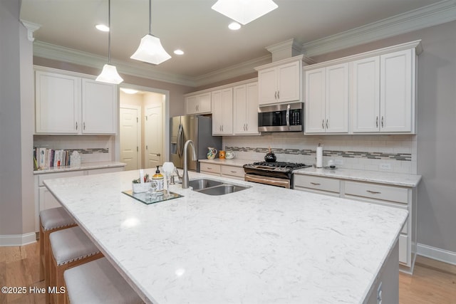 kitchen with an island with sink, stainless steel appliances, white cabinetry, and sink