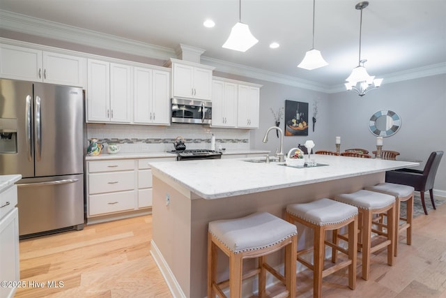 kitchen featuring sink, white cabinetry, stainless steel appliances, and an island with sink