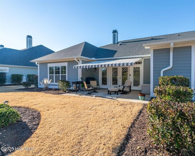 back of property with a lawn and a patio area