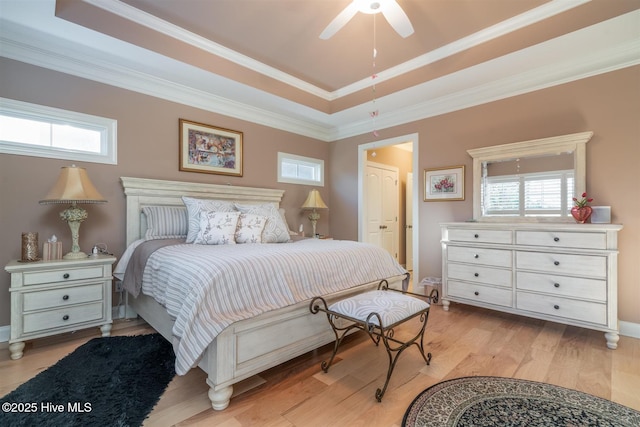 bedroom featuring light wood-type flooring, a tray ceiling, ceiling fan, and crown molding