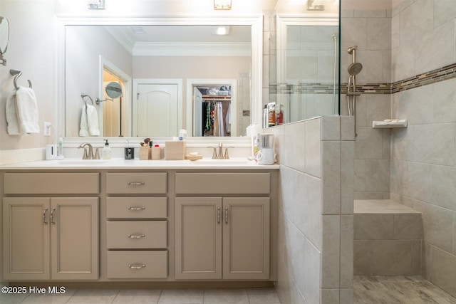 bathroom featuring tile patterned flooring, vanity, ornamental molding, and tiled shower