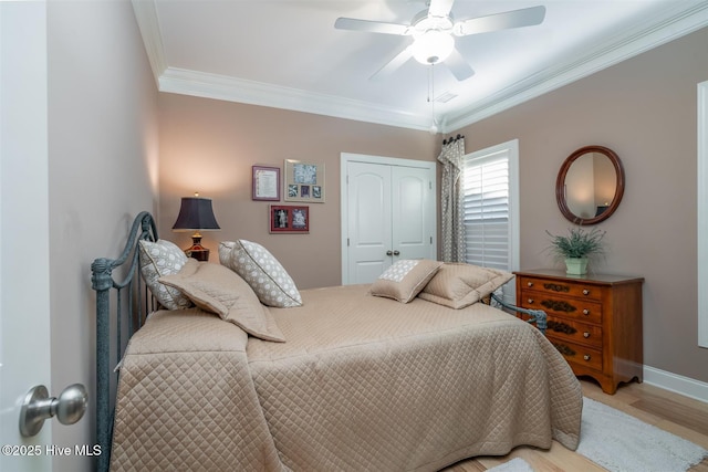 bedroom with ceiling fan, light hardwood / wood-style floors, crown molding, and a closet