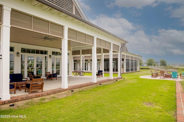 rear view of property with an outdoor fire pit, ceiling fan, a lawn, and a patio