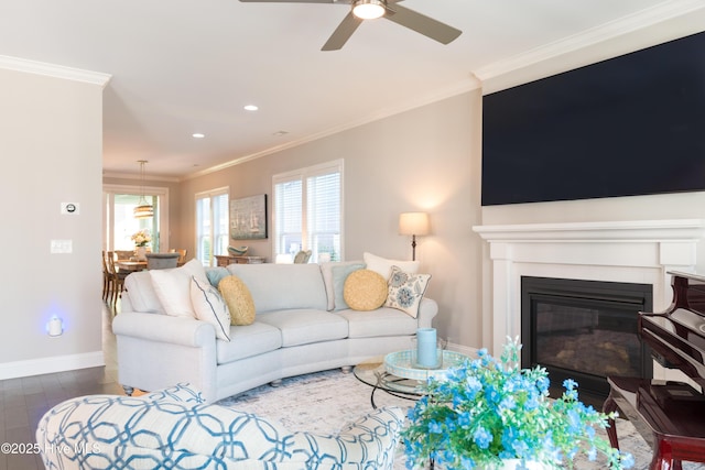 living room featuring a glass covered fireplace, a healthy amount of sunlight, crown molding, and baseboards