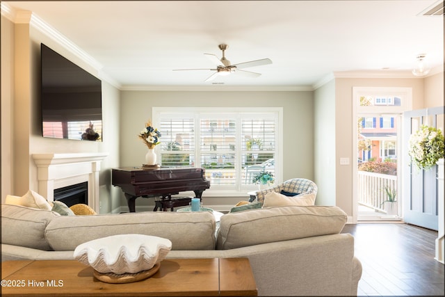 living room with a fireplace, visible vents, crown molding, and wood finished floors