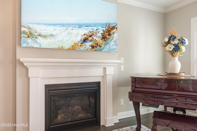 room details featuring ornamental molding, a tile fireplace, baseboards, and wood finished floors