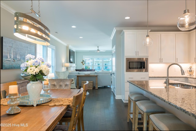 kitchen with ornamental molding, stainless steel microwave, a sink, and a wealth of natural light