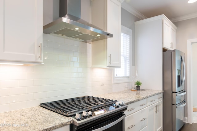 kitchen with range with gas stovetop, wall chimney exhaust hood, ornamental molding, white cabinets, and stainless steel fridge with ice dispenser