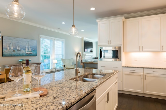 kitchen with crown molding, stainless steel appliances, hanging light fixtures, white cabinetry, and a sink