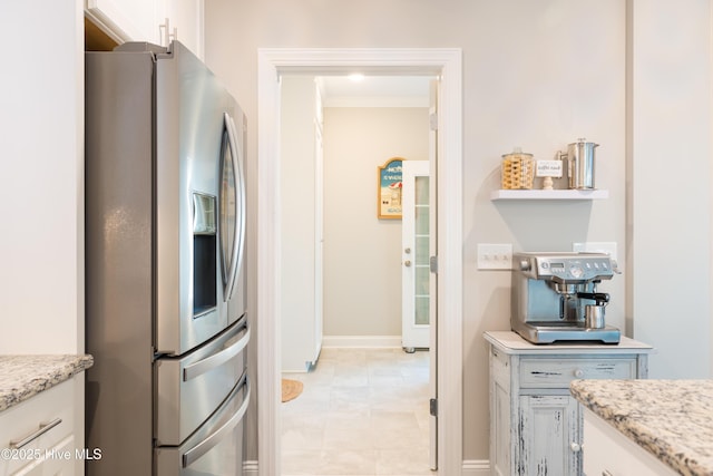 kitchen featuring light stone counters, white cabinets, and stainless steel fridge with ice dispenser