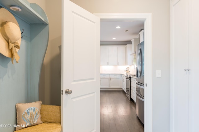 hall with dark wood-style floors, crown molding, and recessed lighting