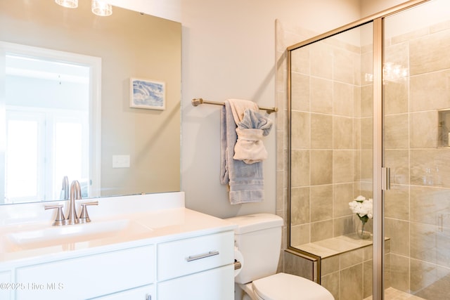 bathroom with a stall shower, vanity, and toilet