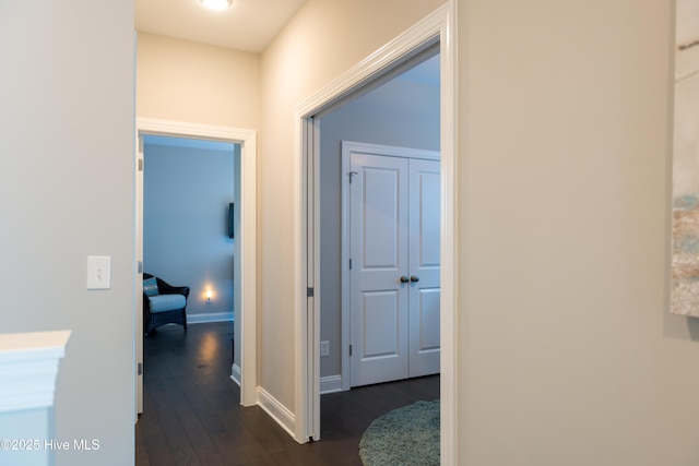 hall featuring baseboards and dark wood-type flooring