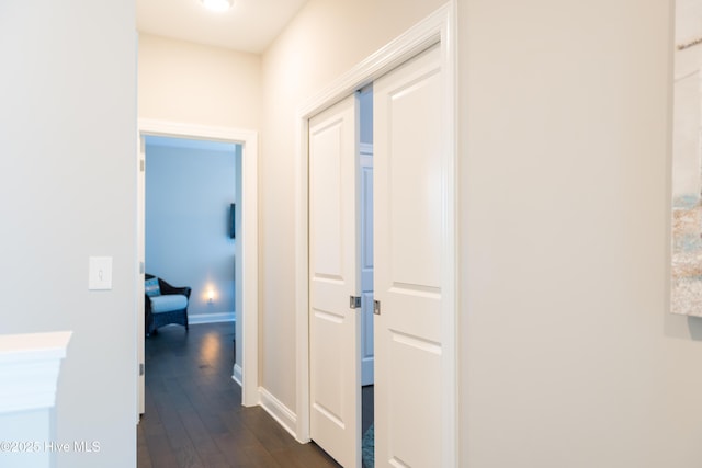 corridor with dark wood-style floors and baseboards