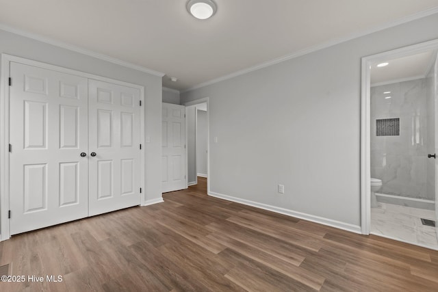 unfurnished bedroom featuring wood-type flooring, connected bathroom, a closet, and ornamental molding