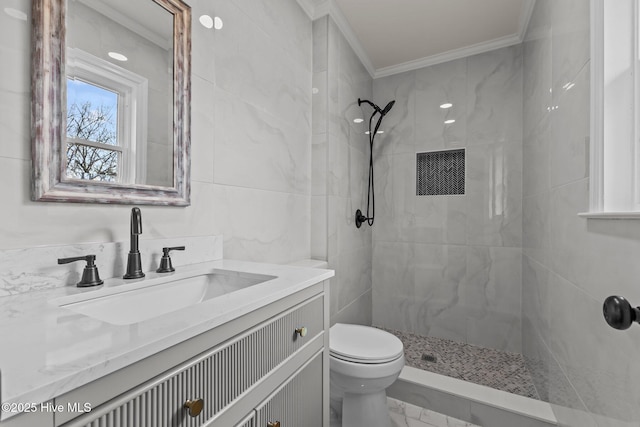 bathroom with ornamental molding, vanity, tiled shower, tile walls, and toilet