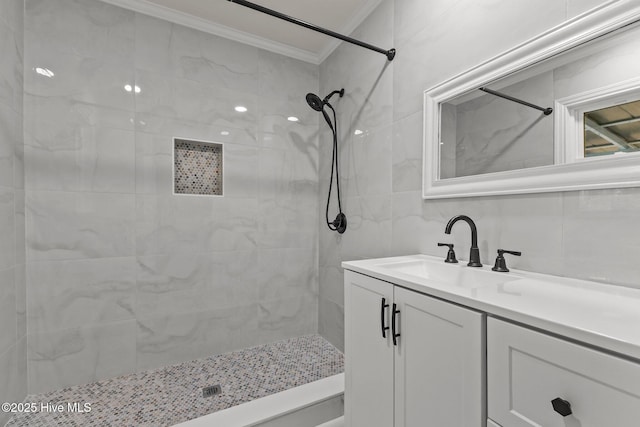 bathroom with vanity, a tile shower, and crown molding